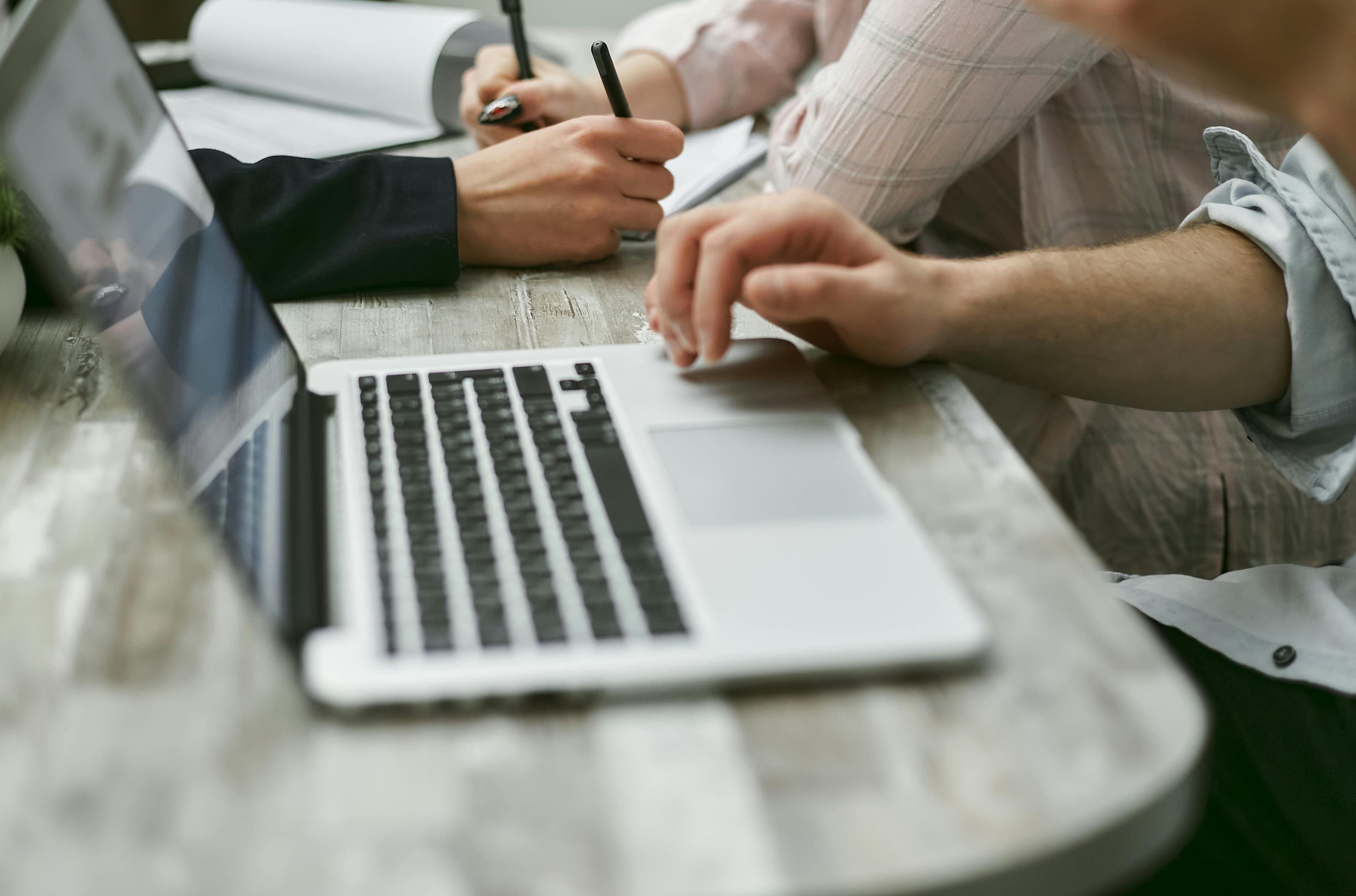 Mesa de trabajo con portátil, documentos y manos revisando una decisión
